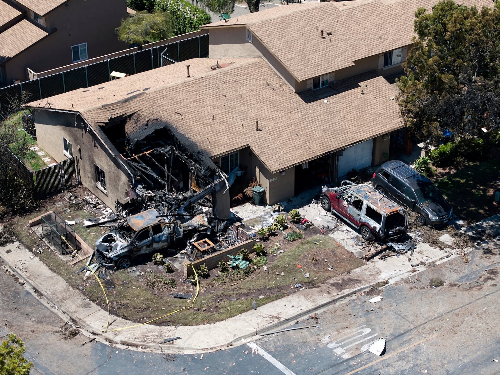 Debris covers the ground after a small plane crashed into a San Diego neighborhood, setting homes and cars on fire and forcing evacuations early Thursday, May 22, 2025. (AP Photo/William Liang)