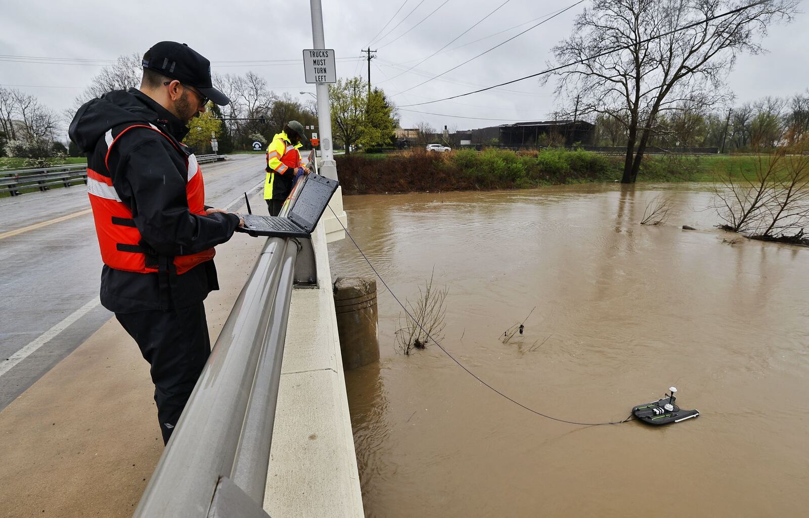 Alex Hackney, left, and Jeremy Bailey, hydrotechs with Miami Conservancy District, collect data at the Great Miami River after several days of heavy rain Saturday, April 5, 2025 on the Ohio 122 bridge in Middletown. NICK GRAHAM/STAFF