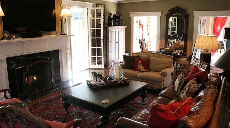 Wide mill work frames the opening into the living room, where boxed windows take in the front view. The wide fireplace is flanked by two sets of French doors accessing the renovated sun porch with its heated travertine-tile floor.