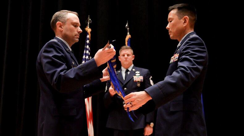 Col. Donald Wilson, Air and Cyberspace Intelligence Group commander, and Lt. Col. Burt Okamoto, Integrated Command, Control, Communications, Computers, Intelligence, Surveillance and Reconnaissance Analysis Squadron commander, reveal the new ACX guidon during a re-designation ceremony Sept. 8 at the National Air and Space Intelligence Center. ACX produces predictive all-source intelligence for the operational, acquisition, and policy making communities on integrated C4ISR capabilities. (U.S. Air Force photo/Senior Airman Samuel N. Earick)