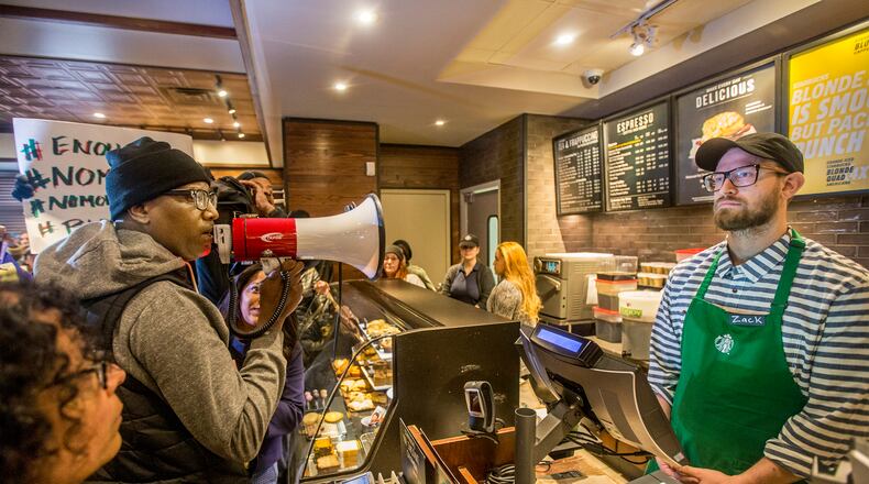 Local Black Lives Matter activist Asa Khalif, left, stands inside the Starbucks at 18th and Spruce, and over a bullhorn, demands the firing of the manager that called police, which resulted in two black men being arrested. On Sunday April 15, 2018, protesters demonstrated outside the Starbucks and planned to return Monday. (Michael Bryant//Philadelphia Inquirer/TNS)