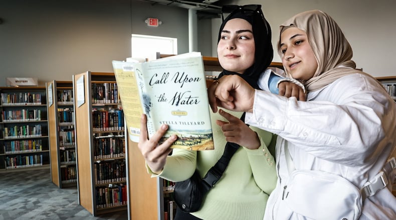 Amina Muradova, left and Aydina Fakhratov, both from Dayton, check out a book during the grand opening of the Dayton Metro Library Huber Heights Branch Friday June 2, 2023. JIM NOELKER/STAFF