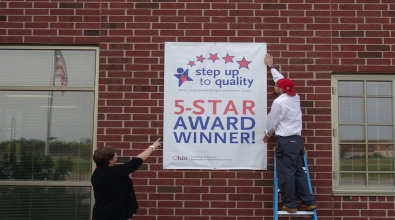 Trotwood Early Learning Center Assistant Principal and pre-school supervisor Tina Ketzer works with head custodian Chase Hamlett to put up the 5-Star Award winning banner from the Ohio Department of Education’s Step-up to Quality rating system. The 5-star rating is the highest the state awards for providing high quality pre-kindergarten education.