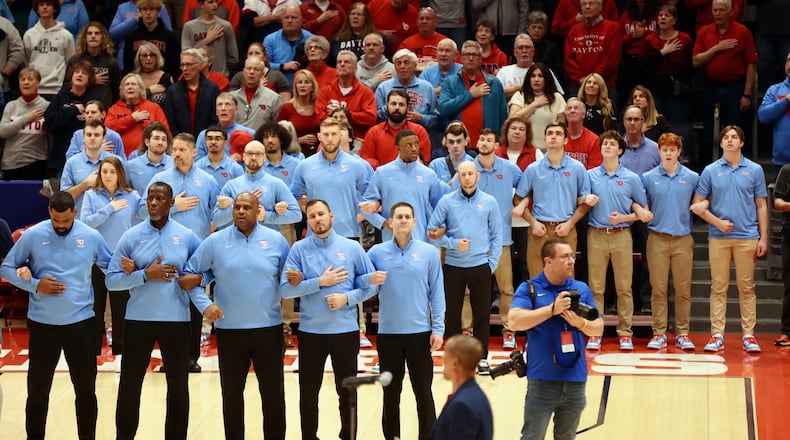 Dayton coaches and staff members stand for the national anthem before a game against St. Bonaventure on Friday, Feb. 2, 2024, at UD Arena. David Jablonski/Staff