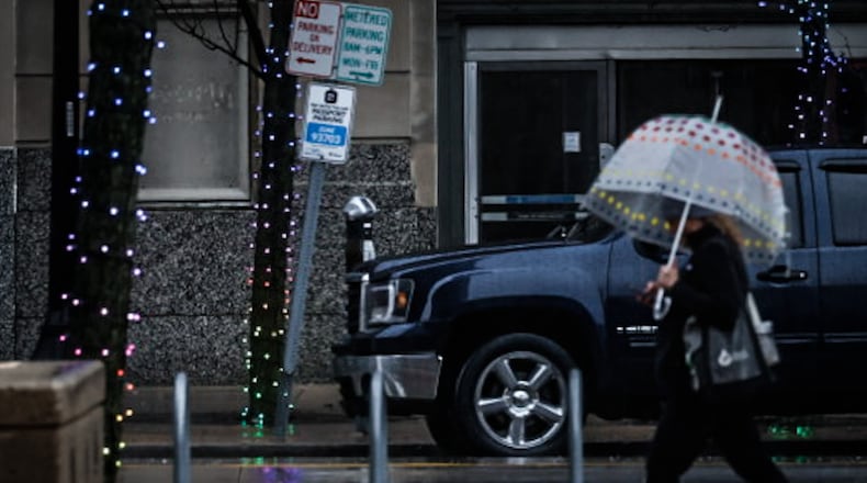 A pedestrian walks on Main Street in downtown Dayton on a rainy Tuesday morning January 9, 2024. JIM NOELKER/STAFF