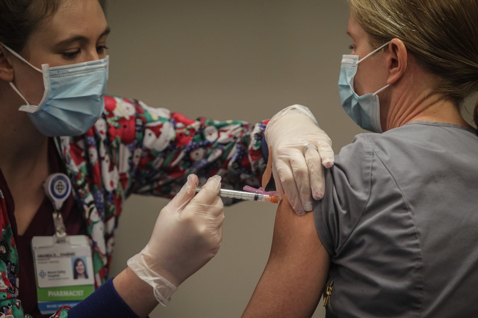 Premier Health pharmacist, Amanda Deskins gives a COVID shot to Miami Valley Hospital emergency room physician Dr. Cathy Marco. who was the first frontline worker at the hospital to be vaccinated Tuesday, Dec. 22, 2020. The COVID-19 vaccine arrived in Dayton Dec. 22, 2020 at Miami Valley Hospital. Doctors and nurses were the first to receive the vaccine. JIM NOELKER/STAFF