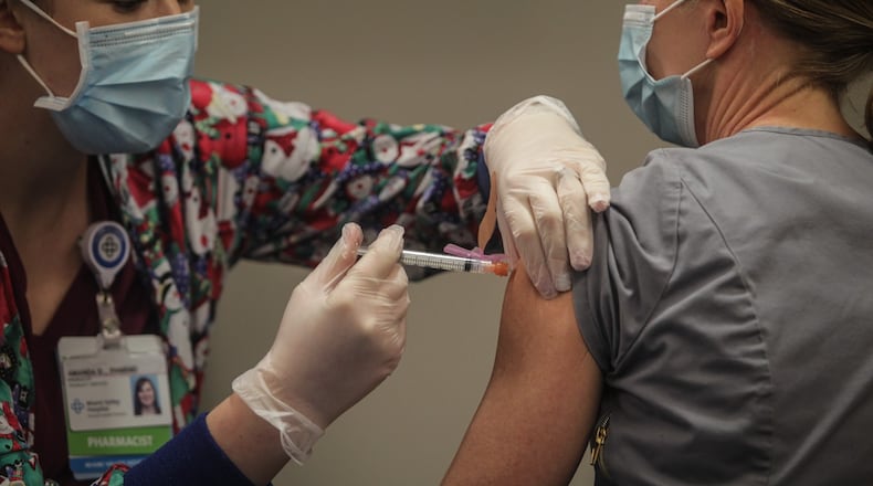 Premier Health pharmacist, Amanda Deskins gives a COVID shot to Miami Valley Hospital emergency room physician Dr. Cathy Marco. who was the first frontline worker at the hospital to be vaccinated Tuesday, Dec. 22, 2020. The COVID-19 vaccine arrived in Dayton Dec. 22, 2020 at Miami Valley Hospital. Doctors and nurses were the first to receive the vaccine. JIM NOELKER/STAFF