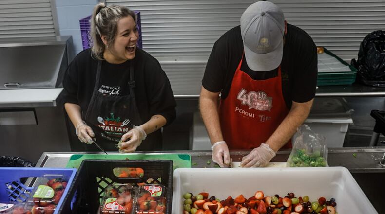 House of Bread volunteers from left, Alli Hachey and Luke Bohardt, create a fruit medley at the House of Bread on Orth Avenue in Dayton. JIM NOELKER/STAFF