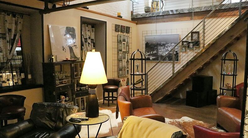 A contemporary-styled metal railing edges the wide solid wood steps to the lower level, where original concrete floors are enhanced with a specially painted finish suggesting granite.