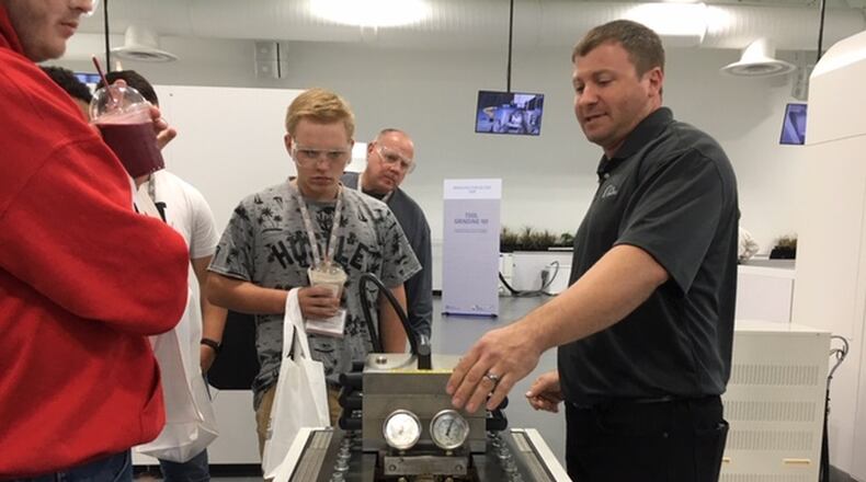 Jeff Gentile, right, a manufacturing services technician, explains his job at Miamisburg’s United Grinding North America to visiting students on Manufacturing Day Friday. THOMAS GNAU/STAFF