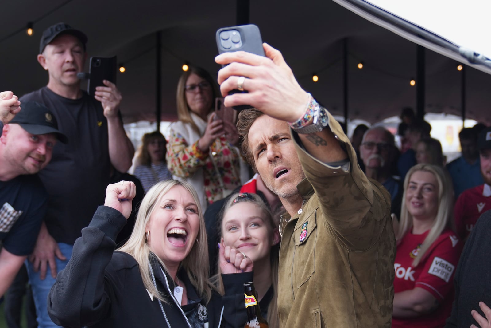 Wrexham co-owner Ryan Reynolds, right, takes a selfie with fans at the Racecourse ground stadium prior to the English League One soccer match between Wrexham and Charlton Athletic in Wrexham, Wales, Saturday, April 26, 2025. (AP Photo/Jon Super)
