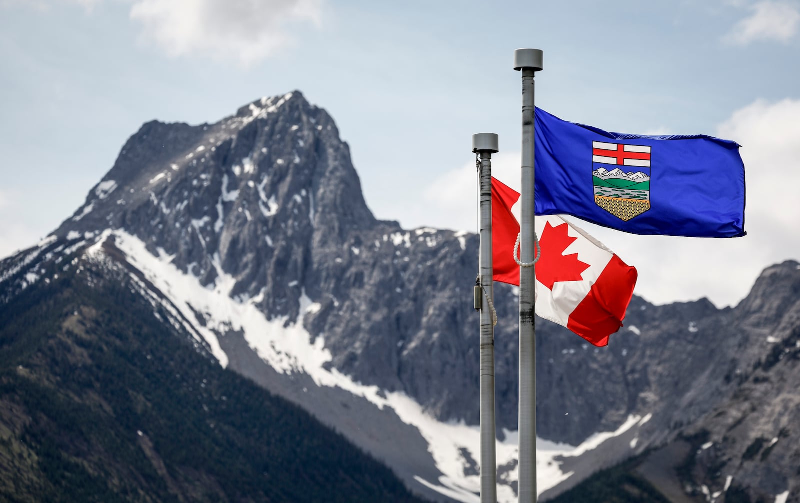 FILE - A Canada flag, left, and an Alberta flag flap in the breeze with Wedge Mountain in the background at the site of the G7 Leaders meeting in Kananaskis, Alberta, June 2, 2025. (Jeff McIntosh/The Canadian Press via AP, file)