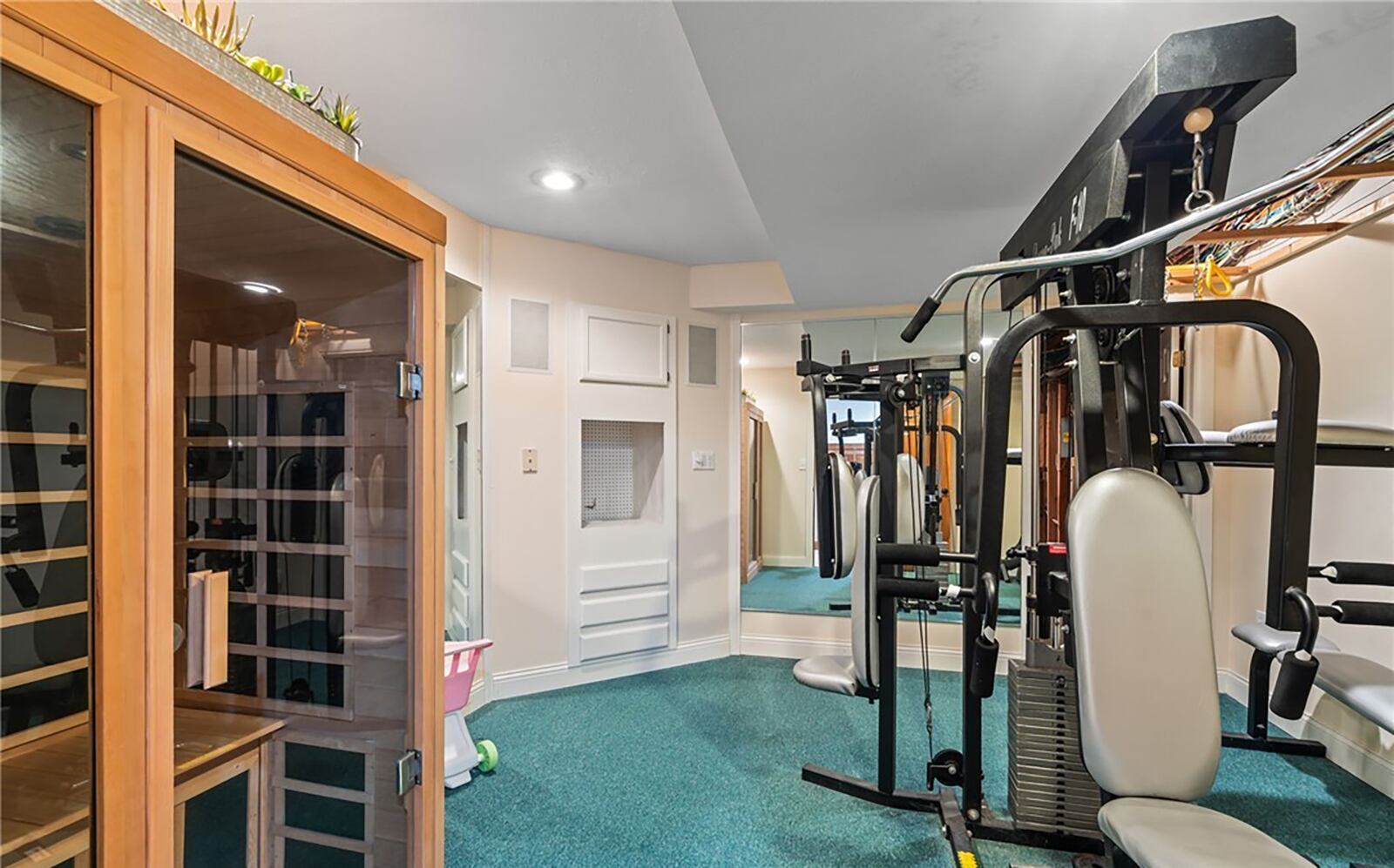 The basement home gym has a sauna and a private spiral staircase leading to the first floor primary suite.