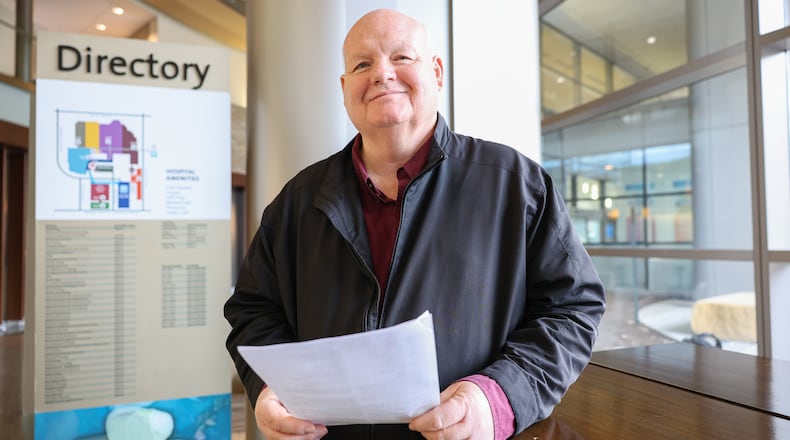 Scott Davidson, who is the pastor of Soul Winners for Jesus Christ on South Main Street in Dayton, smiles after looking over music before singing carols with a group on Monday, Dec. 22 at Miami Valley Hospital in Dayton. Davidson underwent multiple surgeries by Premier Health's Dr. James Ouellette in October and says Dayton is blessed to have such care. The choir also sang at Miami Valley Hospital North and South on Monday. BRYANT BILLING/STAFF