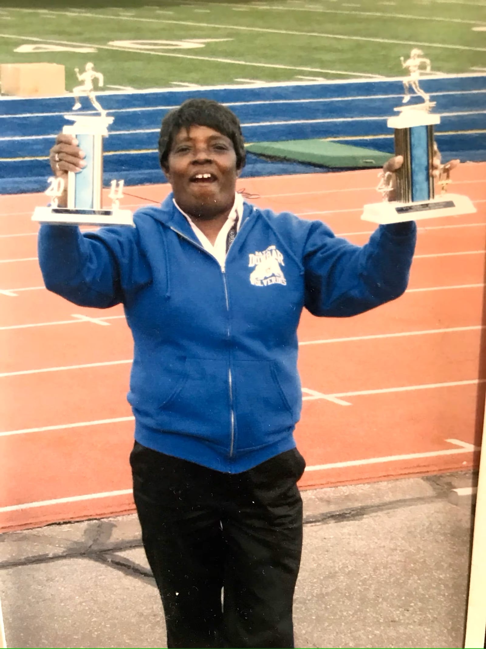 Anna Earley – one of the most successful multi-sport coaches ever during her 50 years in the DPS system, holds the Dayton City League championship trophies her girls and boys track teams at Dunbar won in the early 1990s. CONTRIBUTED