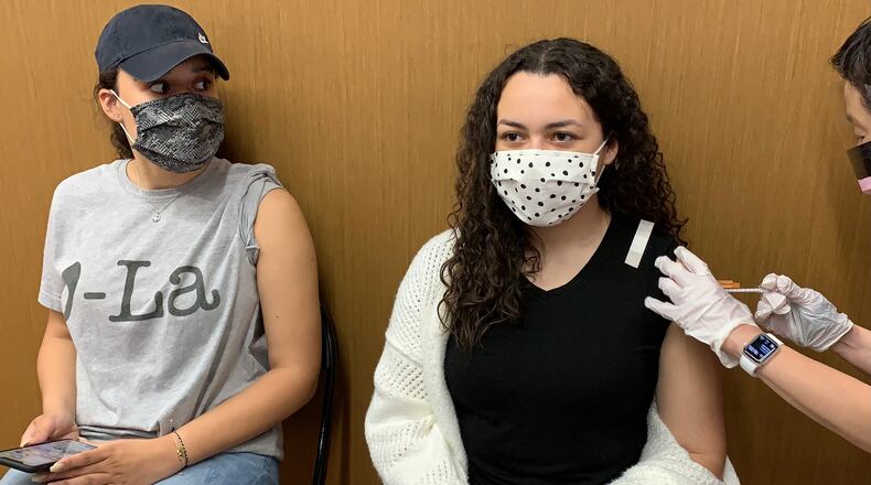 Camille Heard, 16, of Liberty Twp. gets her first dose of the coronavirus vaccine on Monday at the University of Dayton Arena while her 20-year-old sister Chloe Heard waits her turn.