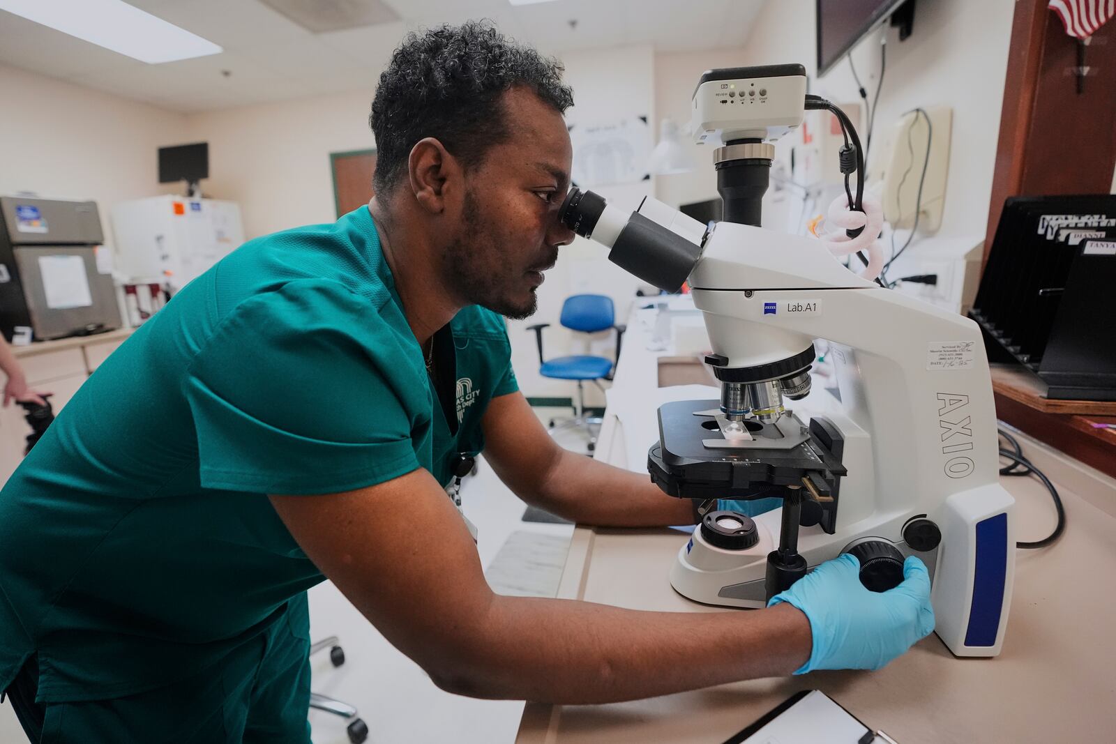 Laboratory technician Asfaw Ayana examines a sample at the Kansas City Department of Public Health, Wednesday, April 9, 2025, in Kansas City, Mo. (AP Photo/Charlie Riedel)