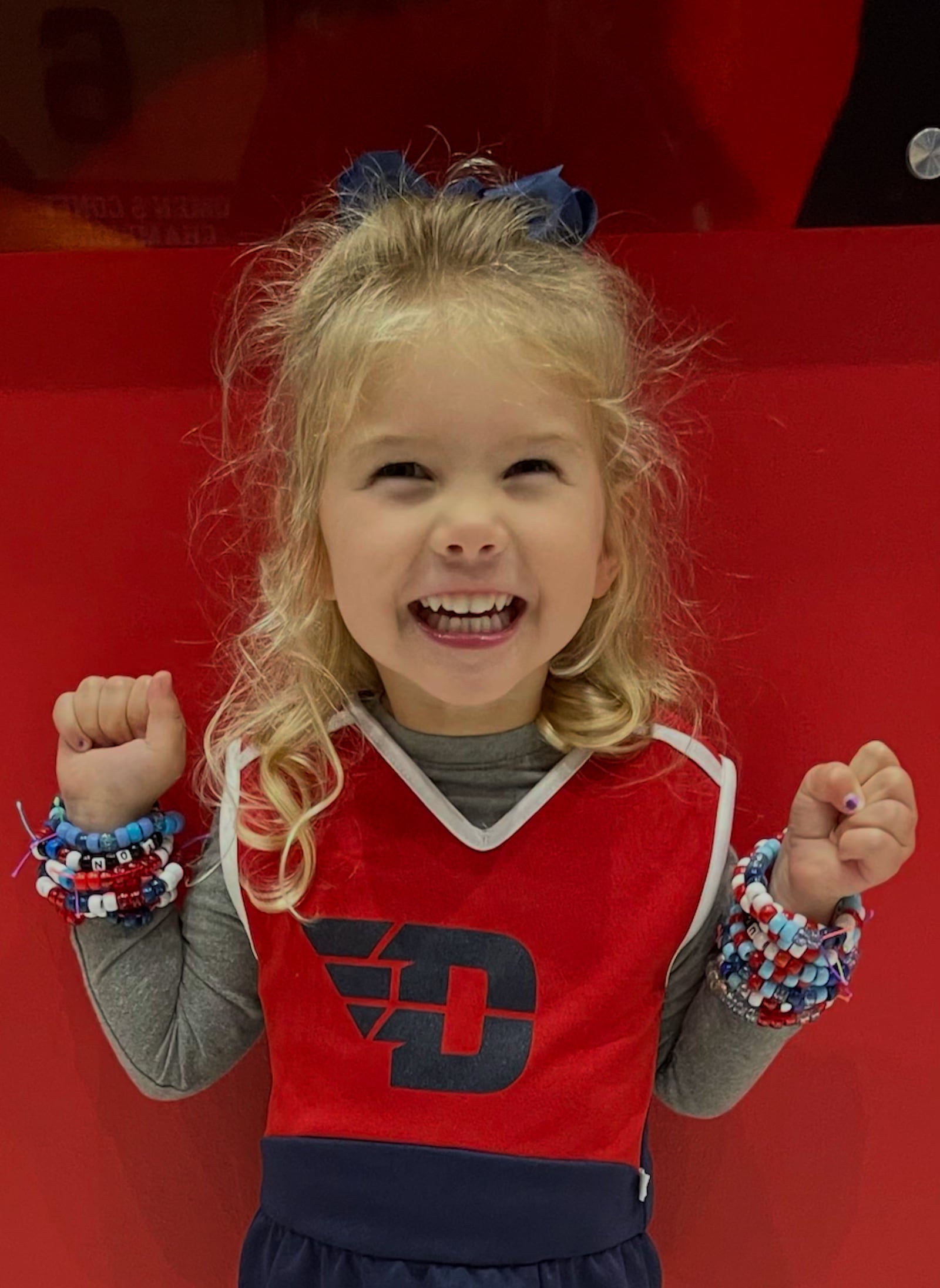 Dayton fan Caroline Kremer, 4, shows off the friendship bracelets she made for the Flyers players and cheerleaders at UD Arena during a game in 2025. Contributed photo