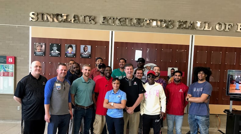 JEFF 1 – Sinclair Community College basketball coach and athletics director Jeff Price (center, black shirt) is surrounded by some of his former players and a few of his fellow coaches Friday at a good-bye tribute to him outside the school’s gymnasium. With sports suspended at Sinclair since the pandemic hit in March of 2020 – and with seasons already cancelled for the 2021-22 school year – Price is leaving Monday to become the associate head coach at the University of Central Arkansas, an NCAA Division I school  in Conway, Arkansas. Tom Archdeacon/STAFF