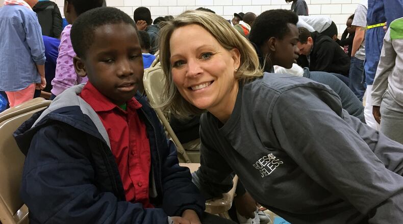 Shoes 4 the Shoeless volunteer, Jenny Kujawa helps a refugee boy with new shoes. The organization goes to schools and neighborhoods in need and provides new shoes and socks to needy kids. CONTRIBUTED