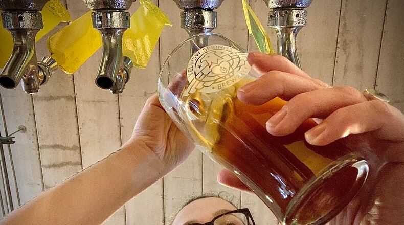 Yellow Springs Brewery bartender, Juliana Crass, pours a cold beer from the tap Thursday, April 20, 2023. The business is celebrating its 10th year anniversary. MARSHALL GORBY \STAFF