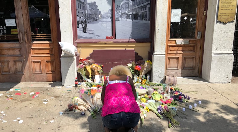 Annette Gibson-Strong cries in front of the memorial to the victims of the Oregon District mass shooting on Monday. She painstakingly moved the memorial so that Ned Peppers Bar could open that day. BONNIE MEIBERS/STAFF