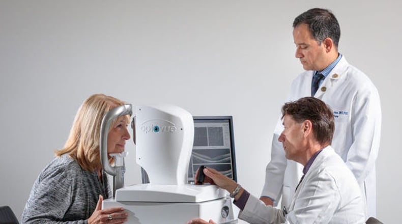Dr. Gregory Van Stavern, seated, and Dr. Rajendra Apte examine the eyes of a woman using technology that one day may make it possible to screen patients for Alzheimer’s disease years before symptoms begin. (Matt Miller/Washington University School of Medicine/TNS)