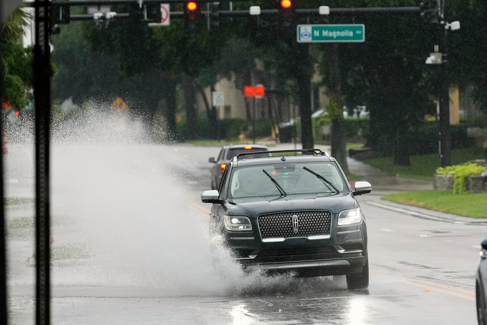 A vehicle drives through a partially flooded street Tuesday, July 15, 2025, as tropical weather moves over Orlando, Fla. (AP Photo/John Raoux)