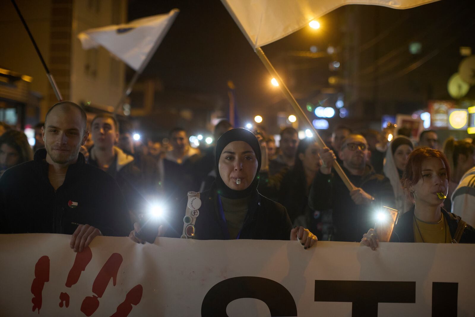 Students blow whistles and carry a banner during an anti-corruption protest in the southwestern town of Novi Pazar, Serbia, Friday, April 11, 2025. (AP Photo/Marko Drobnjakovic)