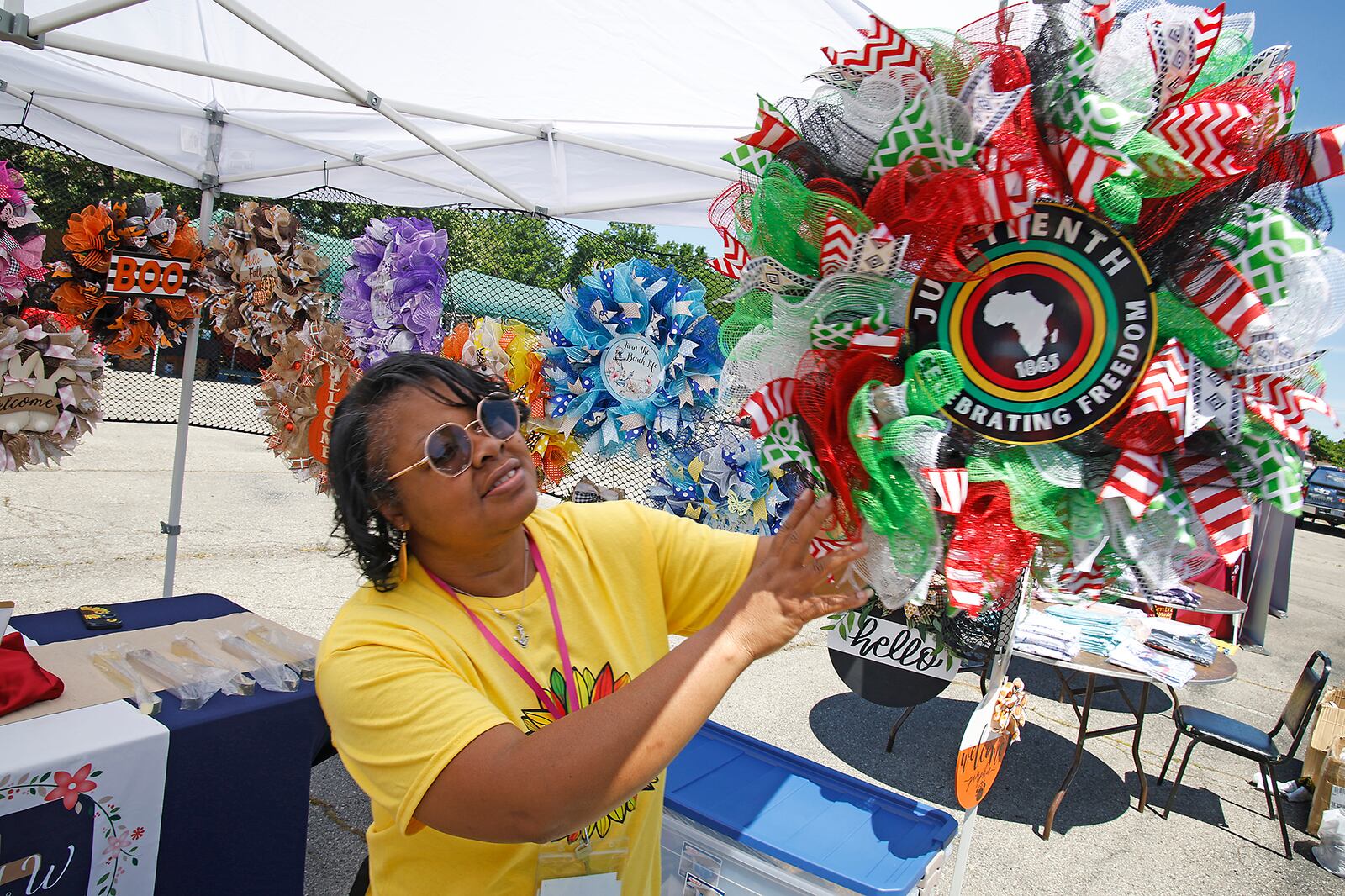 Donna Oliver, from Oh My Wreath, hangs a Juneteenth wreath at her booth Saturday, June 15, 2024 during the annual Juneteenth and Fatherfest Celebration. BILL LACKEY/STAFF