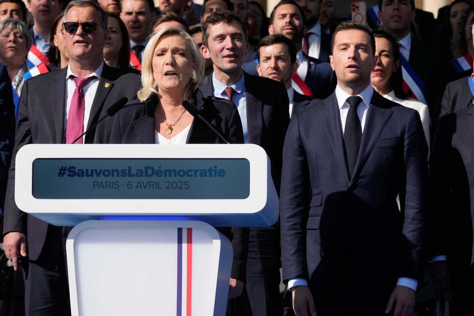 French far-right leader Marine Le Pen, left, delivers her speech with Jordan Bardella during the French far-right party national rally near the parliament in Paris, Sunday, April 6, 2025. (AP Photo/Michel Euler)