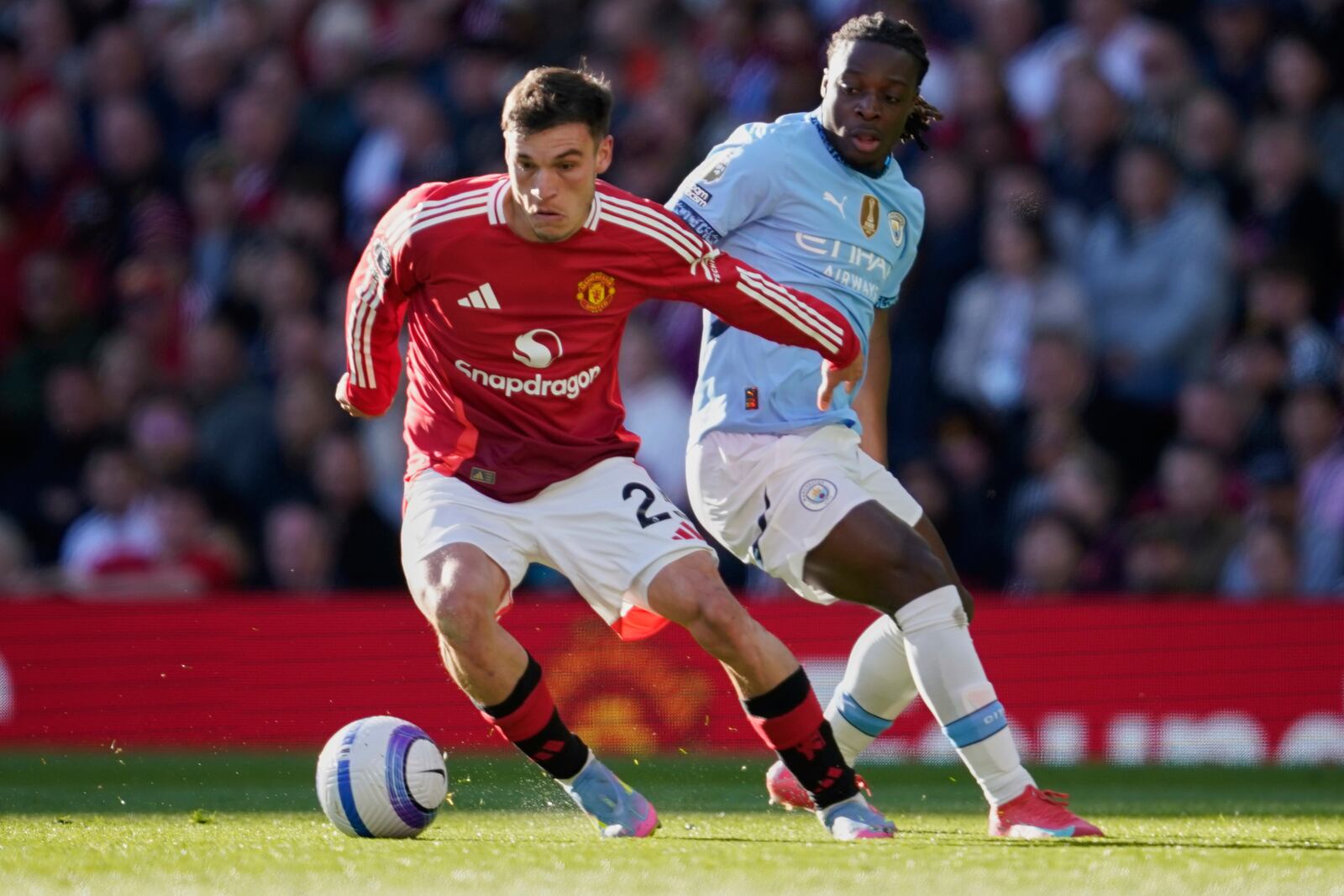 Manchester United's Manuel Ugarte, left, and Manchester City's Jeremy Doku fight for the ball during the English Premier League soccer match between Manchester City and Manchester United in Manchester, England, Sunday, April 6, 2025. (AP Photo/Dave Thompson)