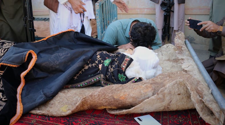 A man mourns next to the body of a child killed in a strike that hit a house in the Momand Dara district of Nangarhar province, Afghanistan, near the border with Pakistan, Friday, March 13, 2026. (AP Photo/Hedayat Shah)
