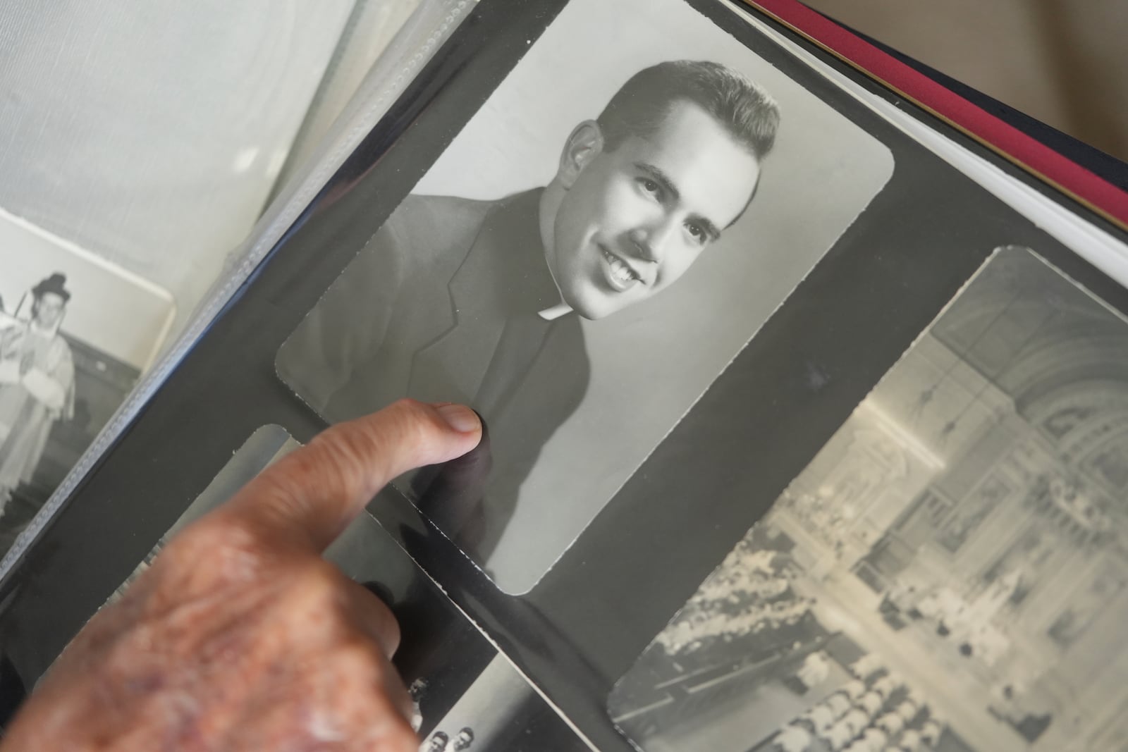 The Rev. James Kelly points to a portrait of himself as a young priest in his photo album during an interview at the Normandy Farms Estates retirement community in Blue Bell, Pa., on Wednesday, June 18, 2025. (AP Photo/Luis Andres Henao)