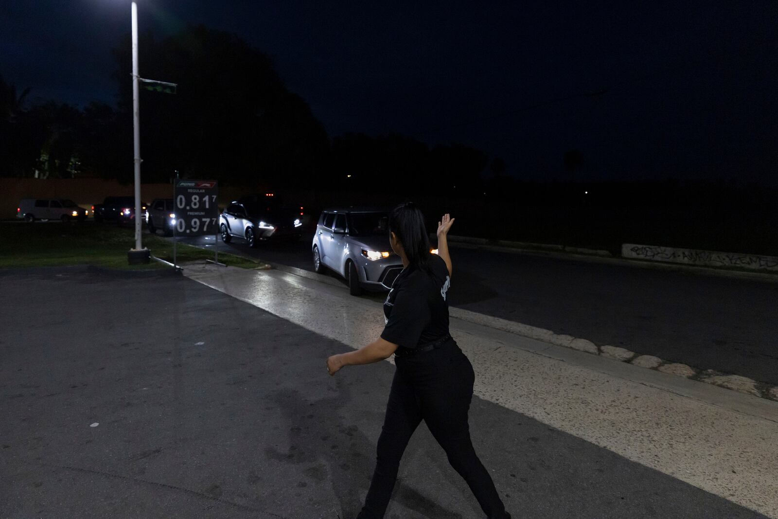 A gas station employee directs traffic as cars line up for fuel during an island-wide blackout in San Juan, Puerto Rico, Wednesday, April 16, 2025. (AP Photo/Alejandro Granadillo)