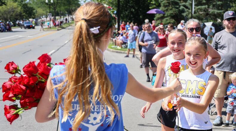 Macy Spalding (right) accepts a rose from someone walking with The Flowerman float during the Americana Festival parade on Friday, July 4 on South Main Street in Centerville. Spalding had recently finished walking the parade route with Centerville Middle School cheerleading. BRYANT BILLING / STAFF