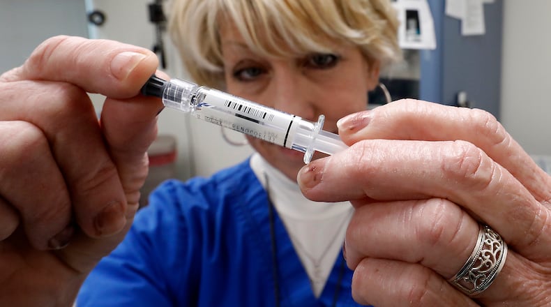 Kellie Adams, a registered nurse at the Clark County Combined Health District, holds up a flu shot Monday, Dec. 18, 2017. BILL LACKEY/STAFF