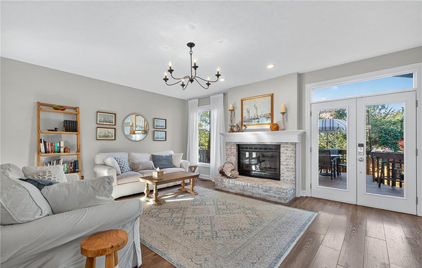 The living room has a fireplace with raised hearth, newer hardwood flooring and recessed lighting. Exterior French doors open to the raised wood deck with railings. CONTRIBUTED