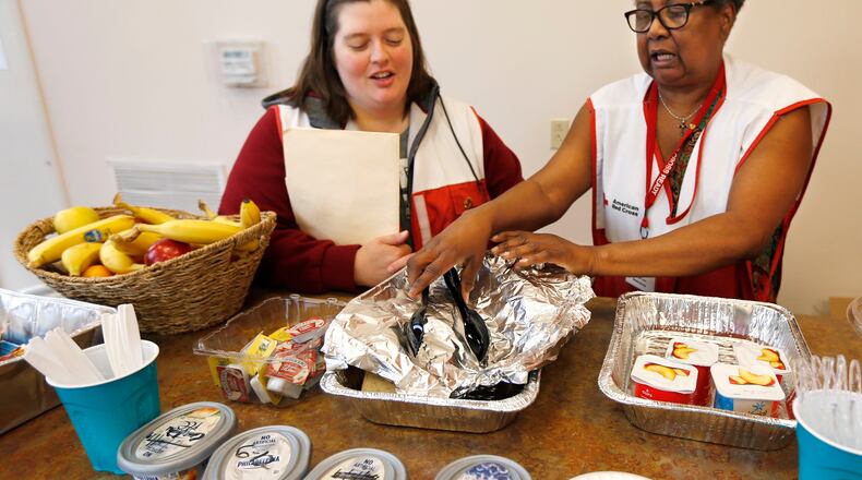 Red Cross Live Safety Asset Protection specialist Danielle Carsner, left, and volunteer Warkoneta Tucker with breakfast offering for shelter clients at Bethesda Temple at Salem Avenue, 3701 Salem Avenue, on June 14. The Red Cross consolidated its shelters to this one location. TY GREENLEES / STAFF