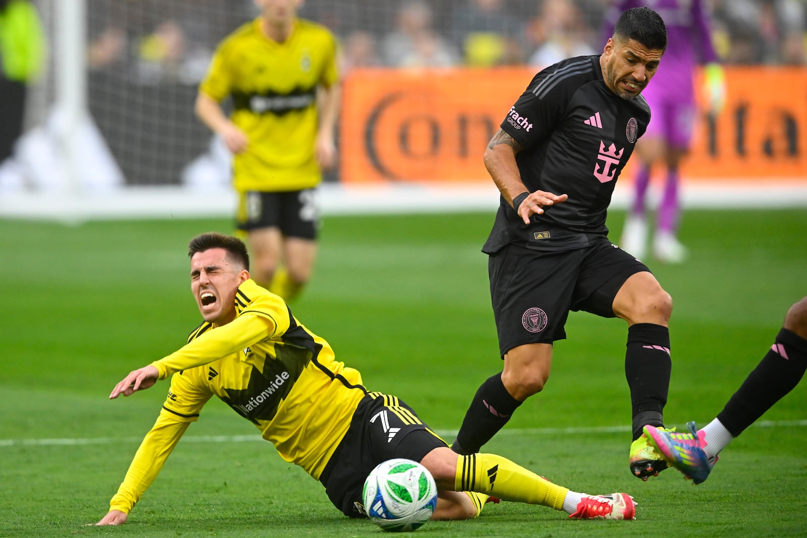 Columbus Crew midfielder Dylan Chambost, left, falls while defended by Inter Miami forward Luis Suarez, right, during the first half of an MLS soccer match Saturday, April 19, 2025, in Cleveland, Ohio. (AP Photo/David Richard)