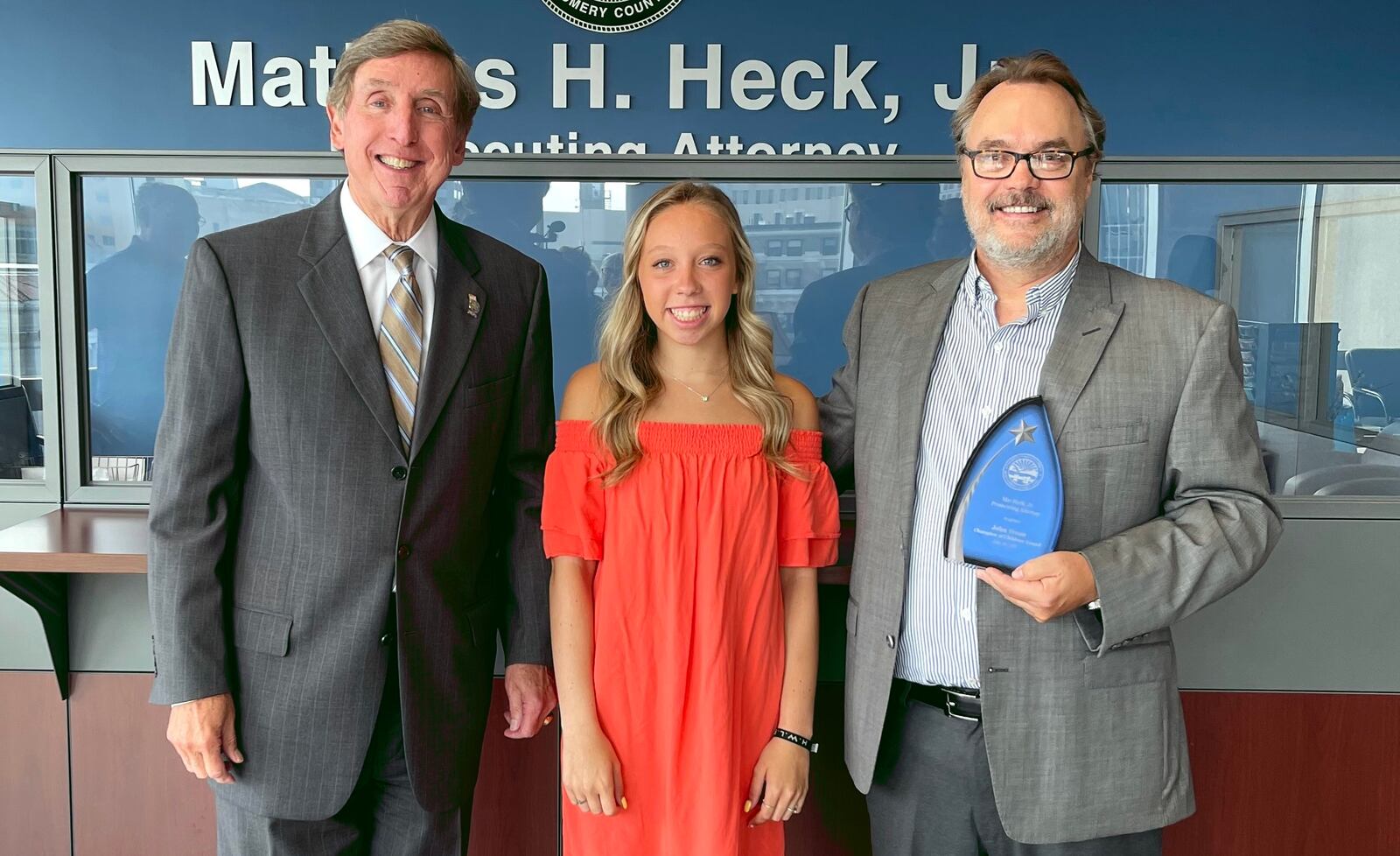 John Treon of Centerville, right, is the recipient of the 2021 Champion of Children Award, who stands with Jemma Manley, the victim of a brutal assault by a man with a mallet; and Montgomery County Prosecutor Mat Heck Jr. Treon confronted Manley's attacker and helped her to his home nearby and called 911.