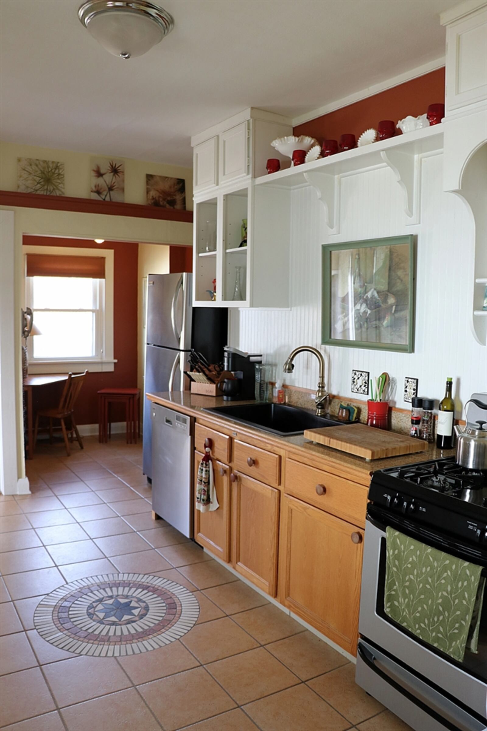 In the kitchen, a mosaic medallion is centered in the ceramic-tile flooring. The breakfast nook has a view of the backyard. 
