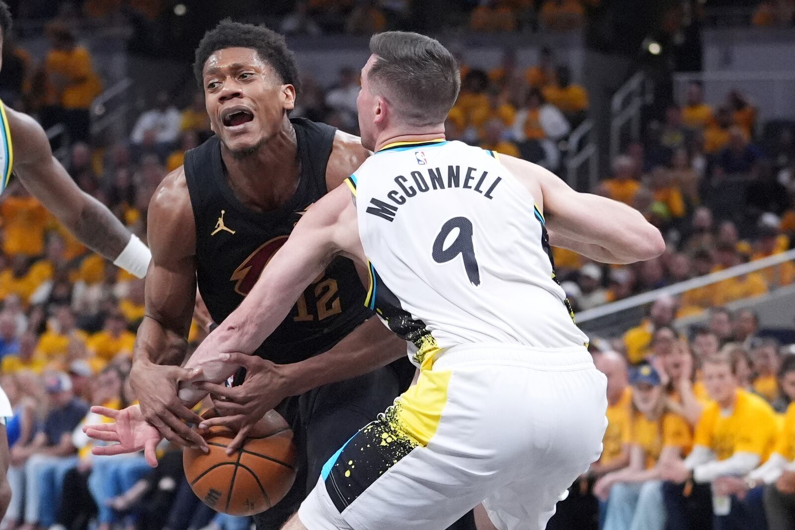 Indiana Pacers guard T.J. McConnell (9) hits the ball away from Cleveland Cavaliers forward De'Andre Hunter (12) during the first half of Game 3 in the Eastern Conference semifinals of the NBA basketball playoffs in Indianapolis, Friday, May 9, 2025. (AP Photo/Michael Conroy)