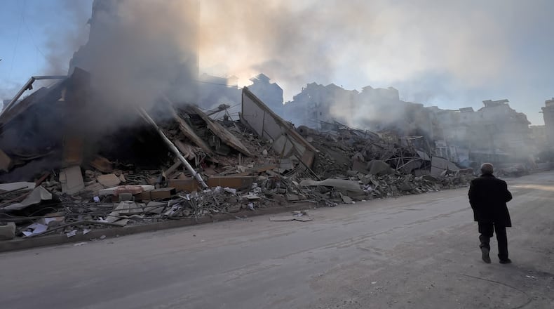 A man passes in front of a destroyed building that housed a branch of Al-Qard Al-Hassan, a non-bank financial institution run by Hezbollah, which was hit by an Israeli airstrike in Dahiyeh, Beirut's southern suburbs, Lebanon, Tuesday, March 10, 2026. (AP Photo/Hussein Malla)