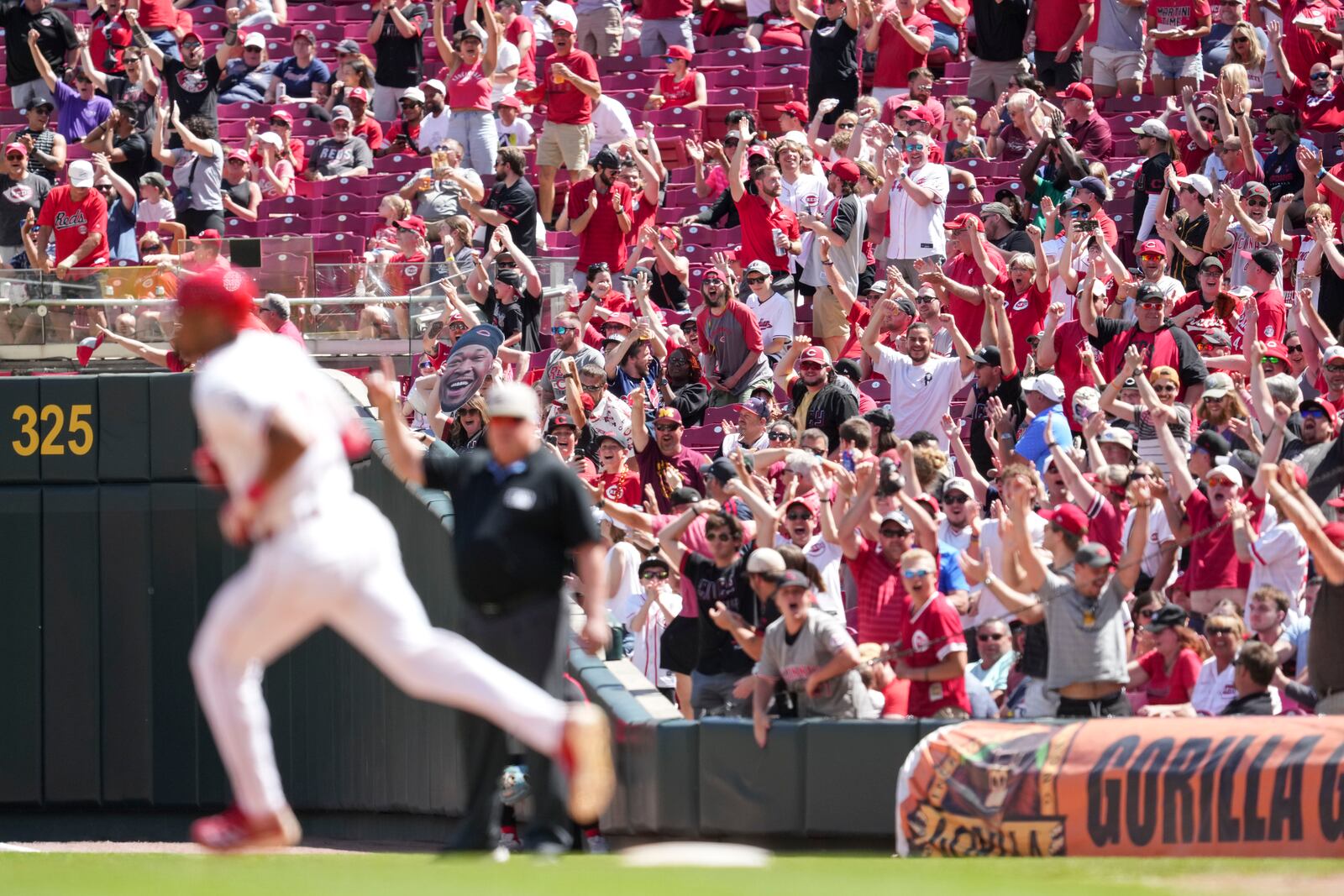 Fans, background, react as Cincinnati Reds' Will Benson, left, rounds the bases after hitting a solo home run during the sixth inning of a baseball game against the Cleveland Guardians, Sunday, May 18, 2025, in Cincinnati. (AP Photo/Jeff Dean)