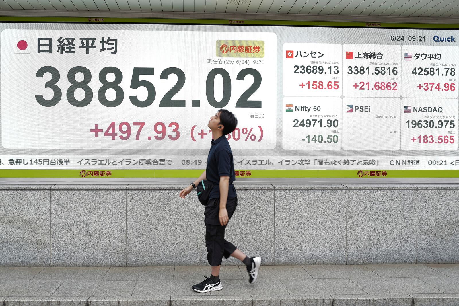 A person walks in front of an electronic stock board showing Japan's Nikkei index at a securities firm Tuesday, June 24, 2025, in Tokyo. (AP Photo/Eugene Hoshiko)