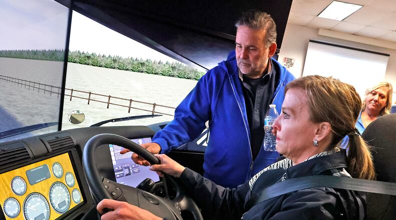 Dr. Jo Alice Blondin, then-president of Clark State College, tries the school's truck driving simulator under the guidance of William Weekley, training manager of the Clark State CDL program, Feb. 21, 2023 during an open house to showcase the simulator. BILL LACKEY/STAFF