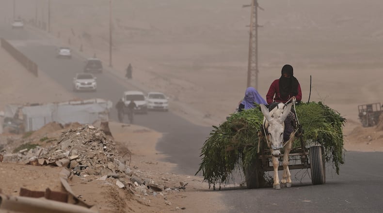 Palestinian women ride a donkey cart along the coastal road in Wadi Gaza during a dust storm in the central Gaza Strip, Saturday, Feb. 14, 2026. (AP Photo/Abdel Kareem Hana)