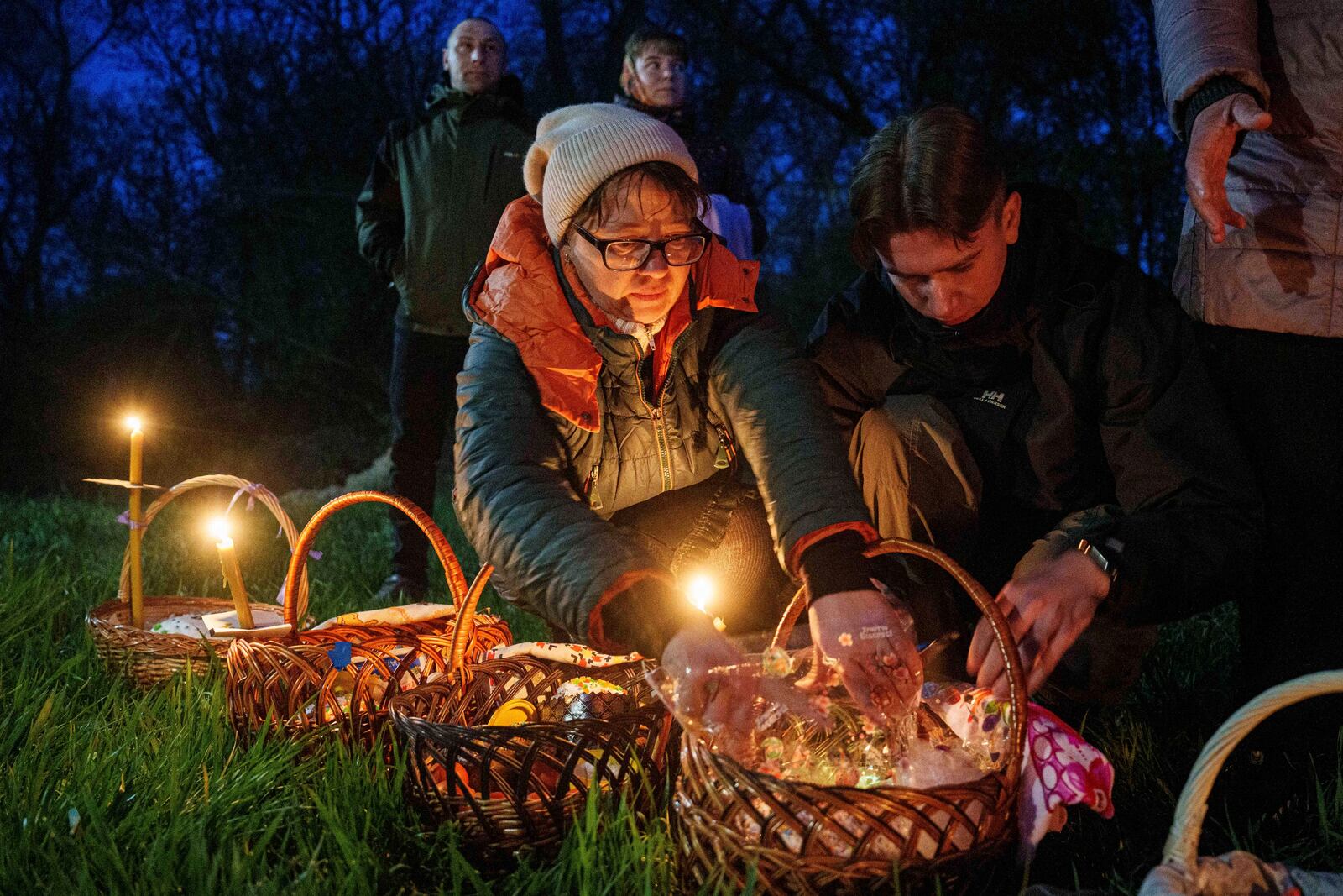 People prepare their Easter baskets to be blessed in front of a church destroyed in fighting between Russian and Ukrainian forces, during celebration of the Orthodox Easter in Lukashivka village, Ukraine, on Sunday, April 20, 2025. (AP Photo/Evgeniy Maloletka)