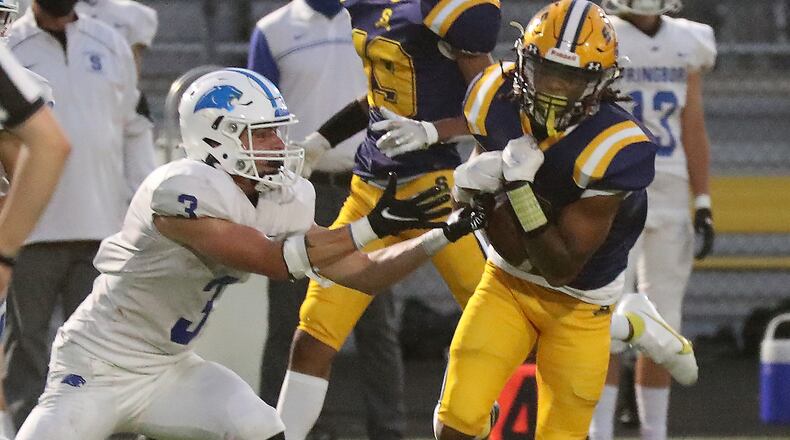 Springfield's Robert Jordan catches a pass across the middle under pressure from Springboro's Titan Case. BILL LACKEY/STAFF